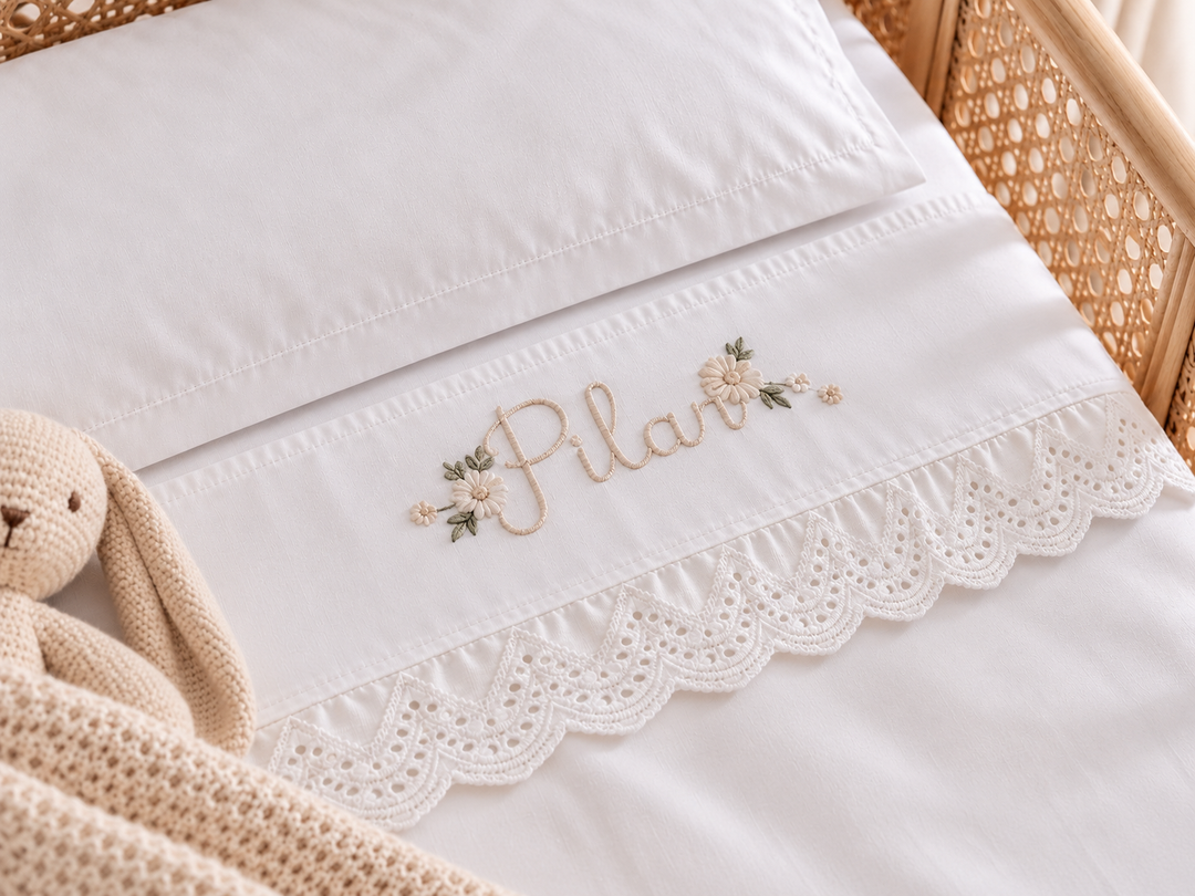 Lençol branco de berço com nome personalizado, flores em tons bege e remate rendilhado