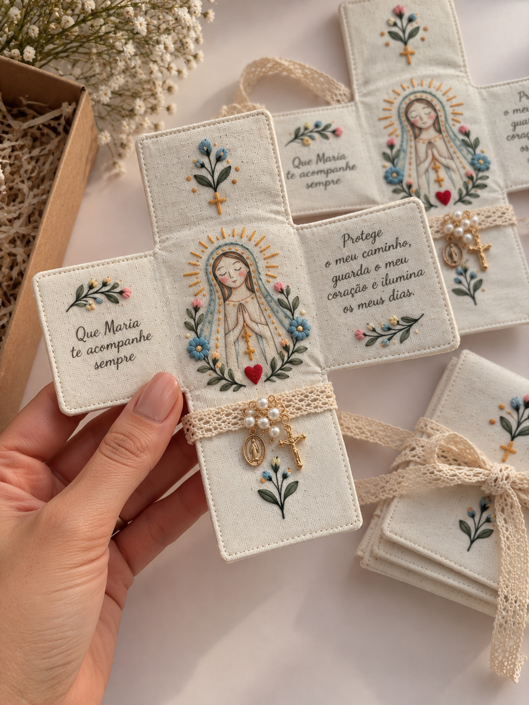 Mão a segurar oratório Maria aberto com flores azuis, mensagens e pequeno terço com medalha